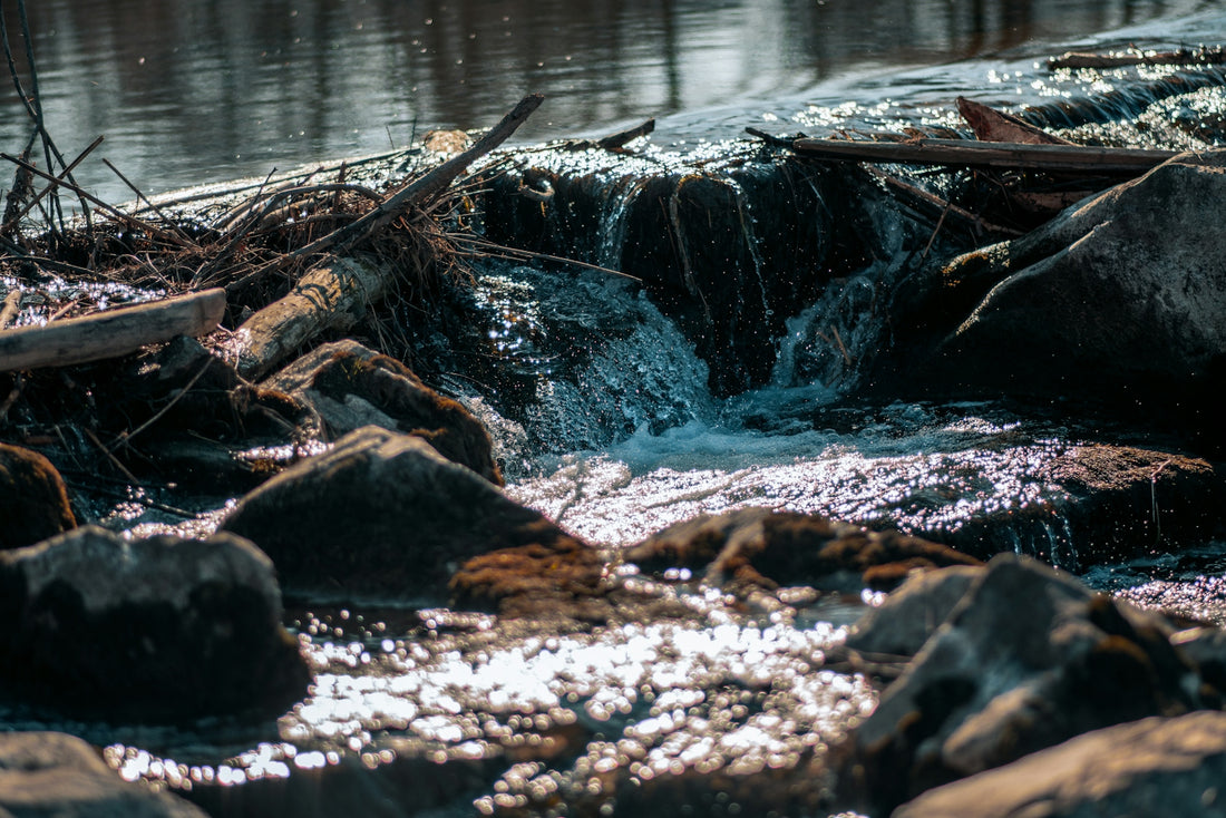 a stream of water running over rocks into a body of water