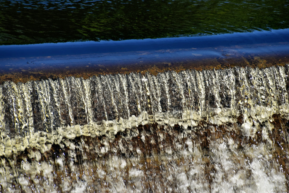 Water cascades over a small dam.