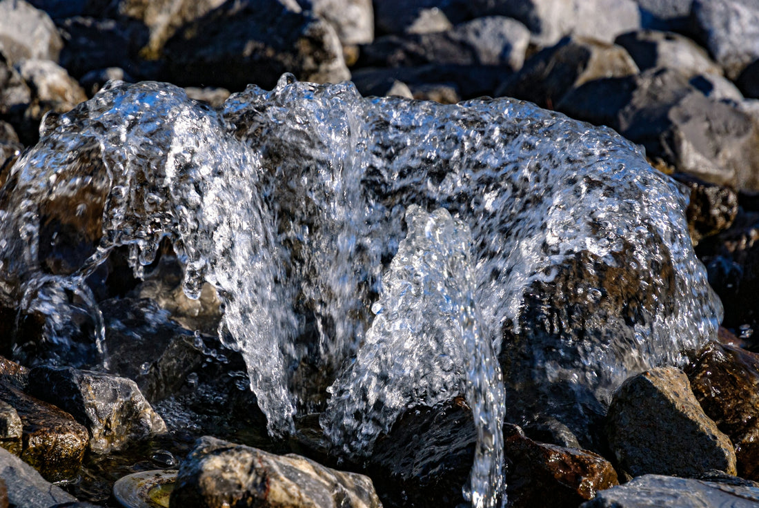 Water splashes over rocks on a sunny day.